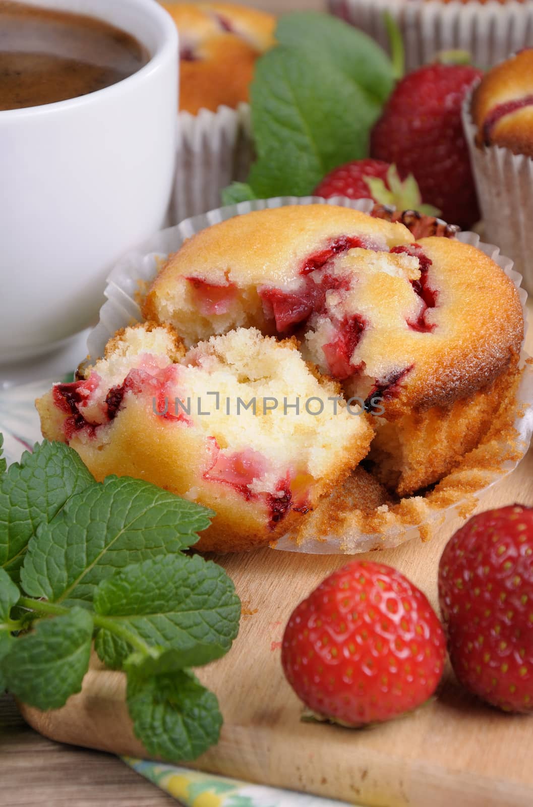 Break muffin with strawberries on a table among the berries and mint