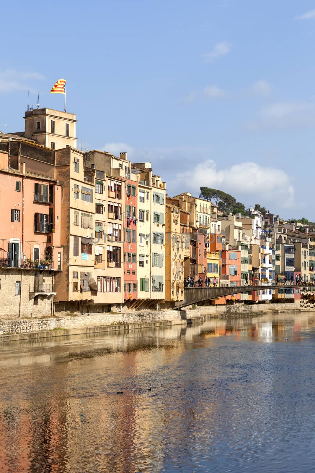 GIRONA, SPAIN - MAY 15, 2016 :Colorful houses on the river Onyar and tourists on the Princess Bridge.  Girona is one of the major Catalan cities.It has one of the largest historical Jewish quarters in Europe.