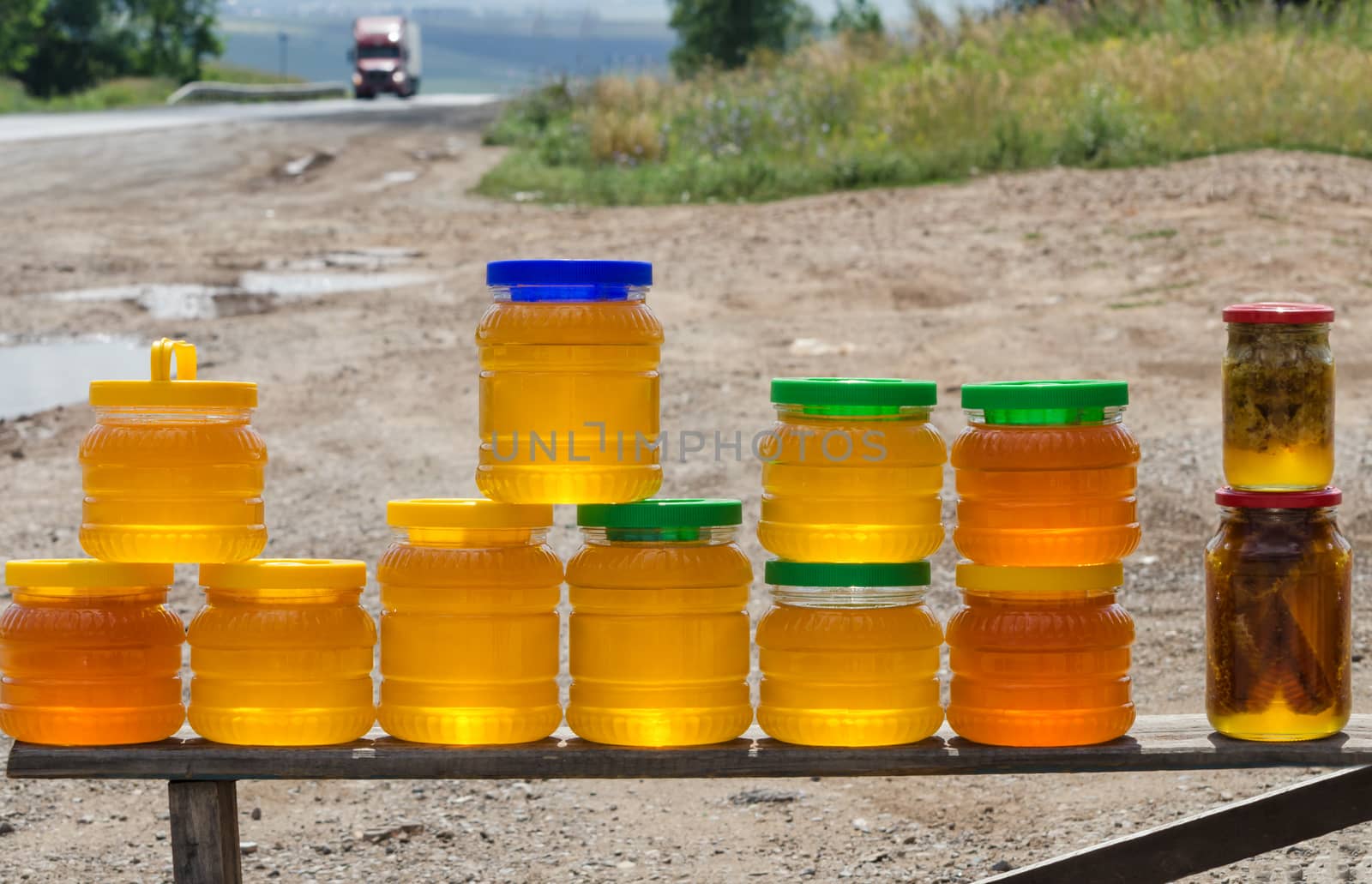 Different varieties of honey in plastic banks for sale beside the road