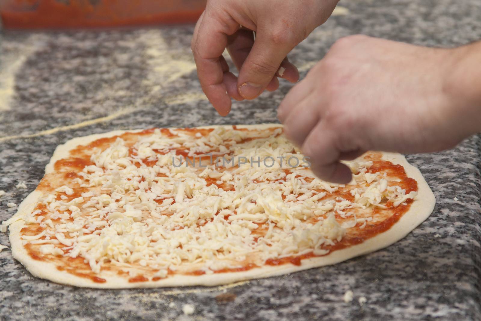 Man chef with raw pizza. Young male in uniform preparing pizza on table.