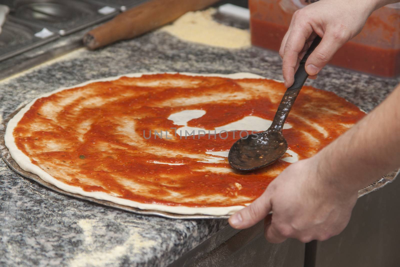 Man chef with raw pizza. Young male in uniform preparing pizza on table.