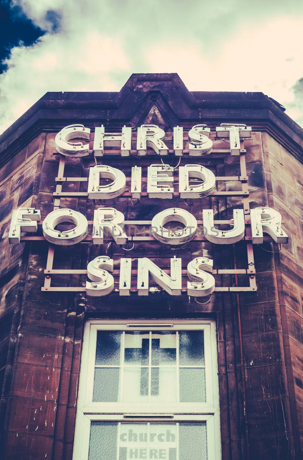 A Neon Sign On An Old Building Saying Christ Died For Our Sins
