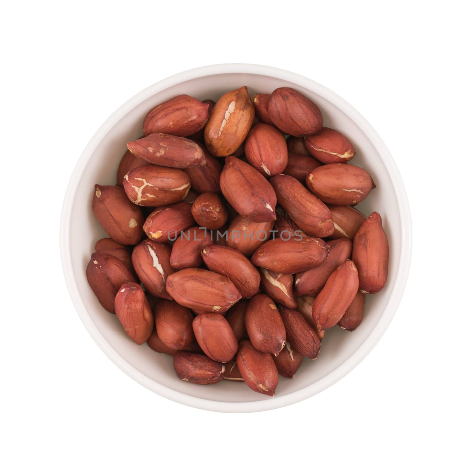 At the center of the frame white bowl roasted peanuts on a white background.  Top view.