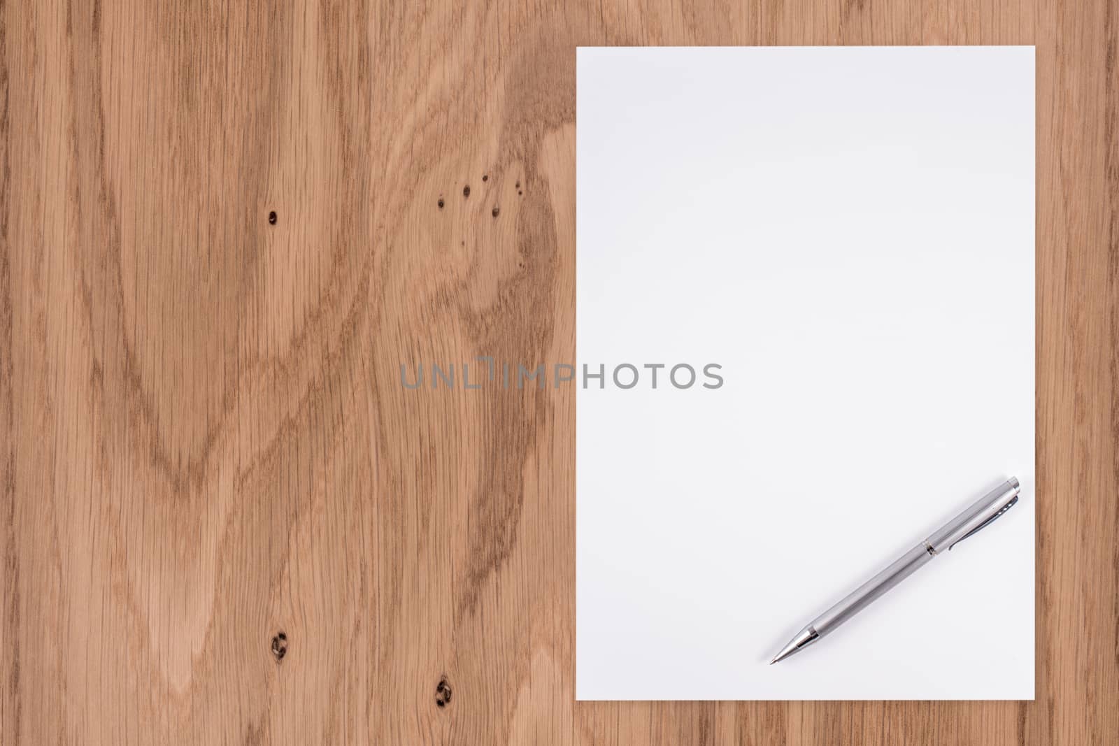 Blank white paper with pen on a wooden desk.