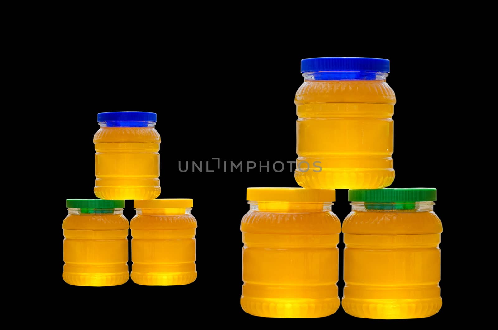 Jars of honey with colorful caps isolated on black background
