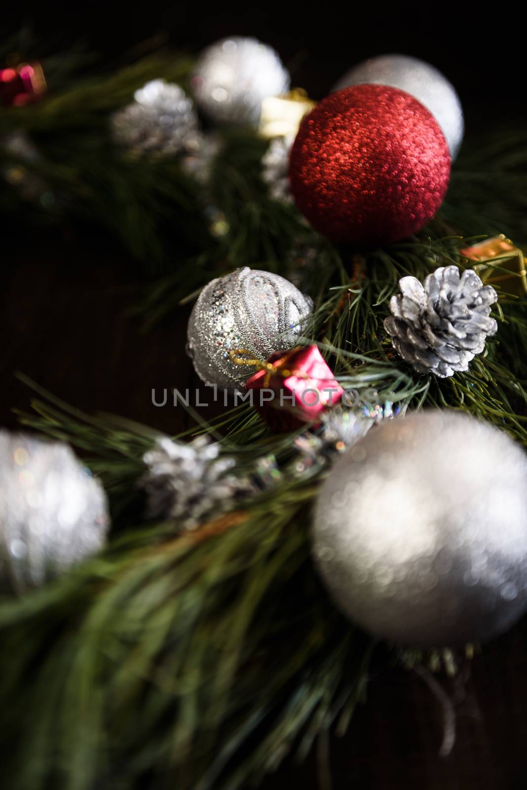 Christmas wreath of fir branches with Christmas decorations, pine cones and gifts on the brown background