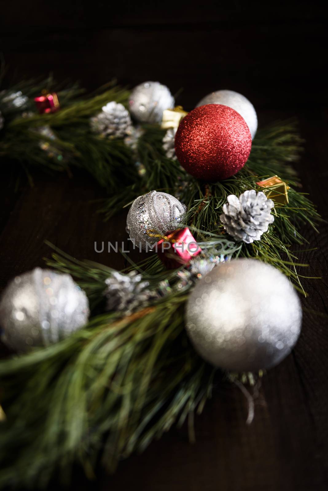 Christmas wreath of fir branches with Christmas decorations, pine cones and gifts on the brown background