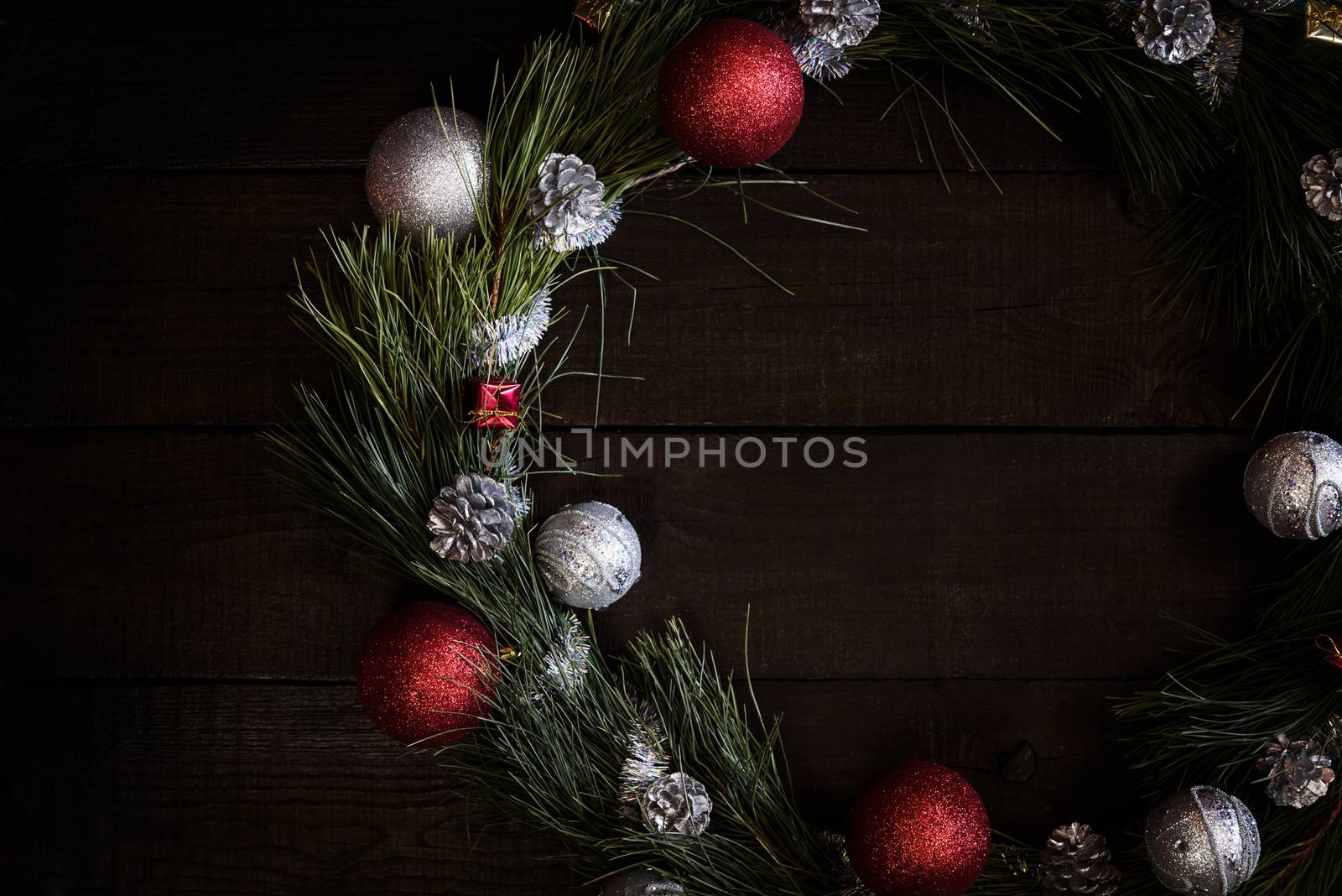 Christmas wreath of fir branches with Christmas decorations, pine cones and gifts on the brown background