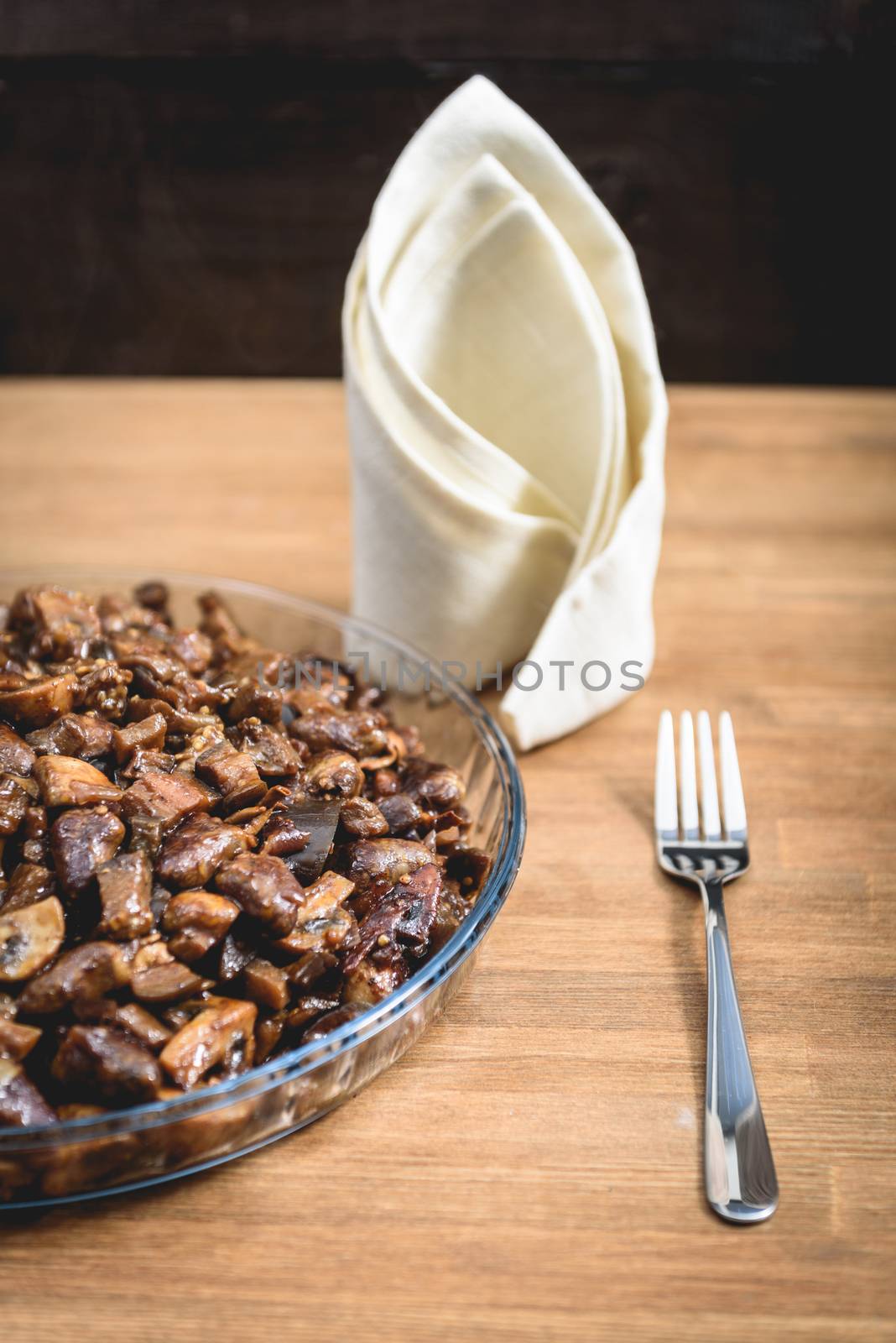 vegetable stew in a glass dish on the table, next fork and napkin