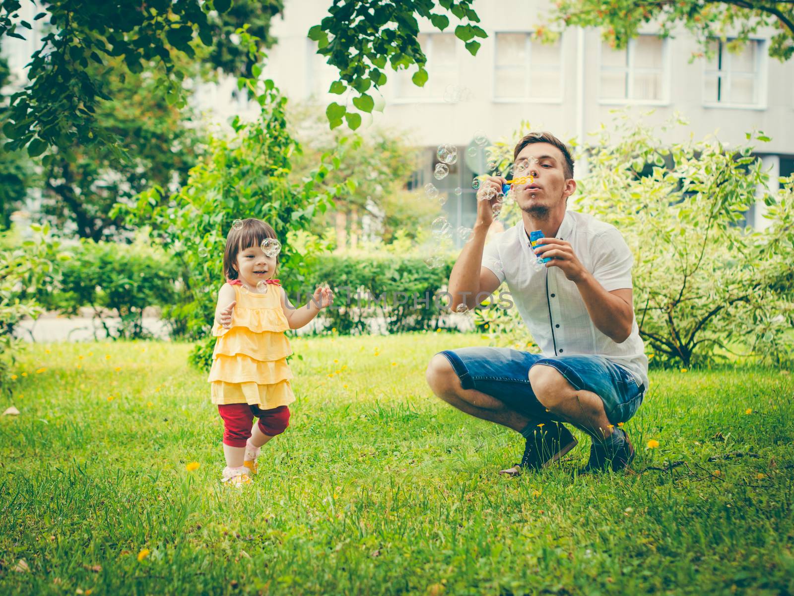 Dad and his daughter are making bubbles in the park. Colorful image for modern lifestyle family concept