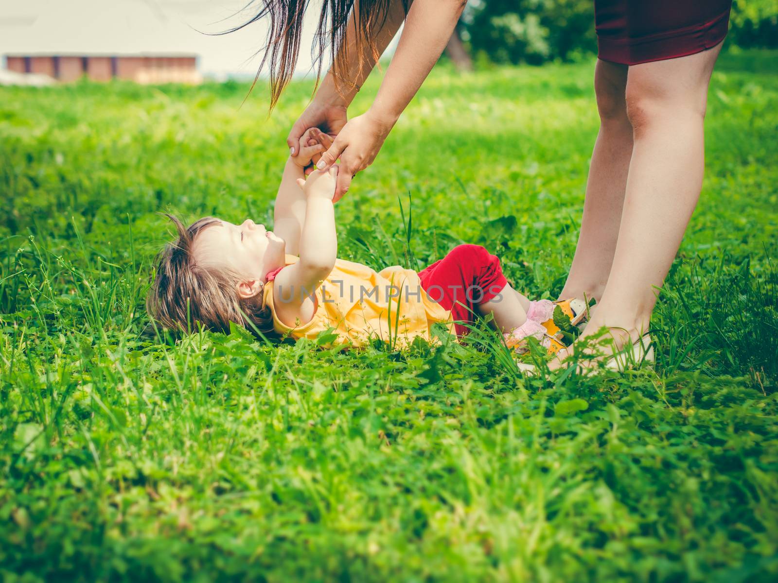 Mother and little daughter playing together on grass in park