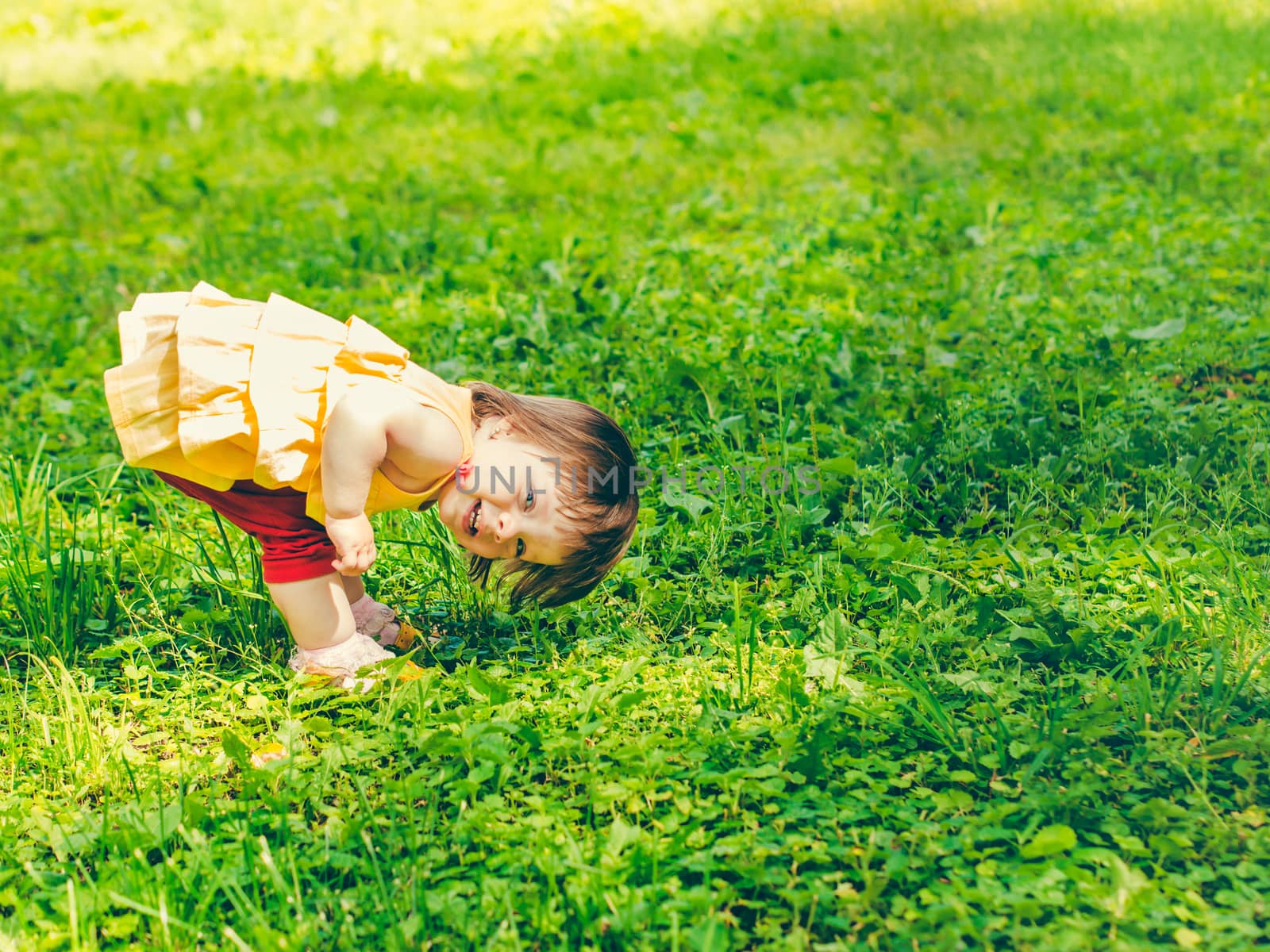 One year baby girl playing upside down outdoors. Adorable little girl image with copy space for your text