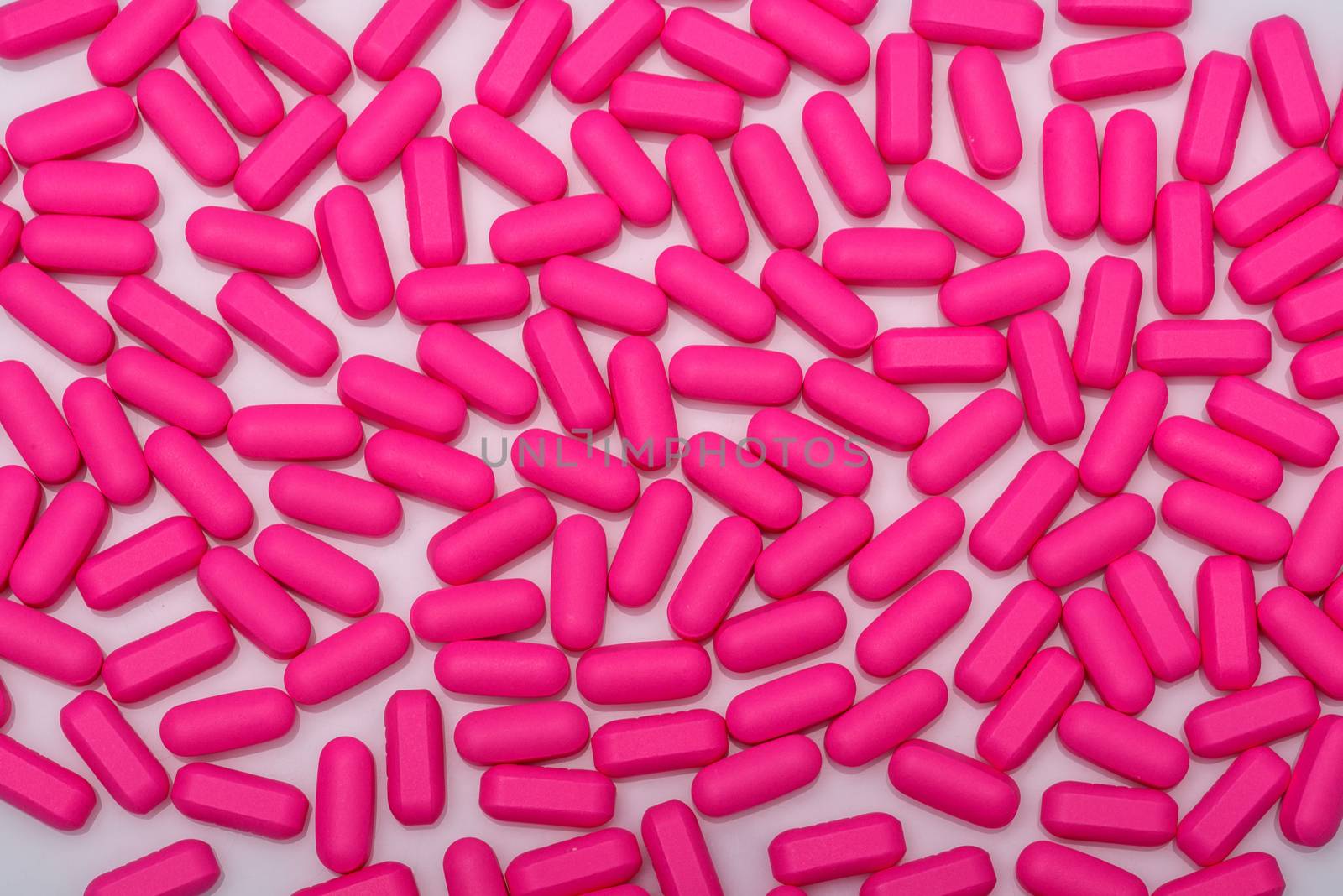 Pills, pink capsules, vitamins on white background