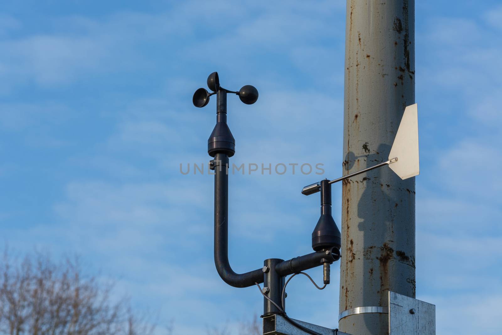 Weather station with anemometer on blue sky.
