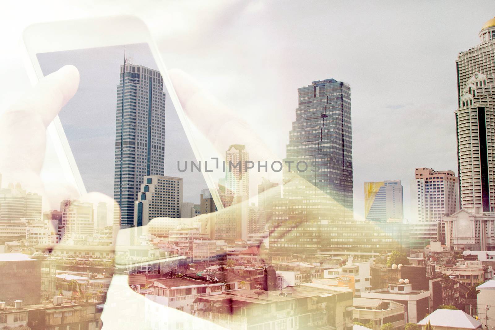 Double exposure image of using smart phone with cityscape background,Communication technology concept