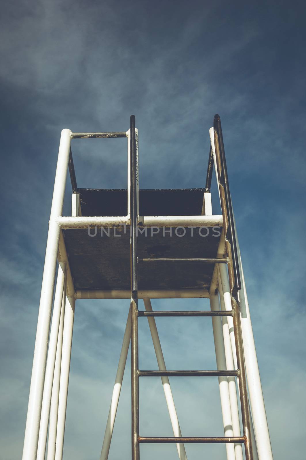 An empty lifeguard tower sits against a blue sky.