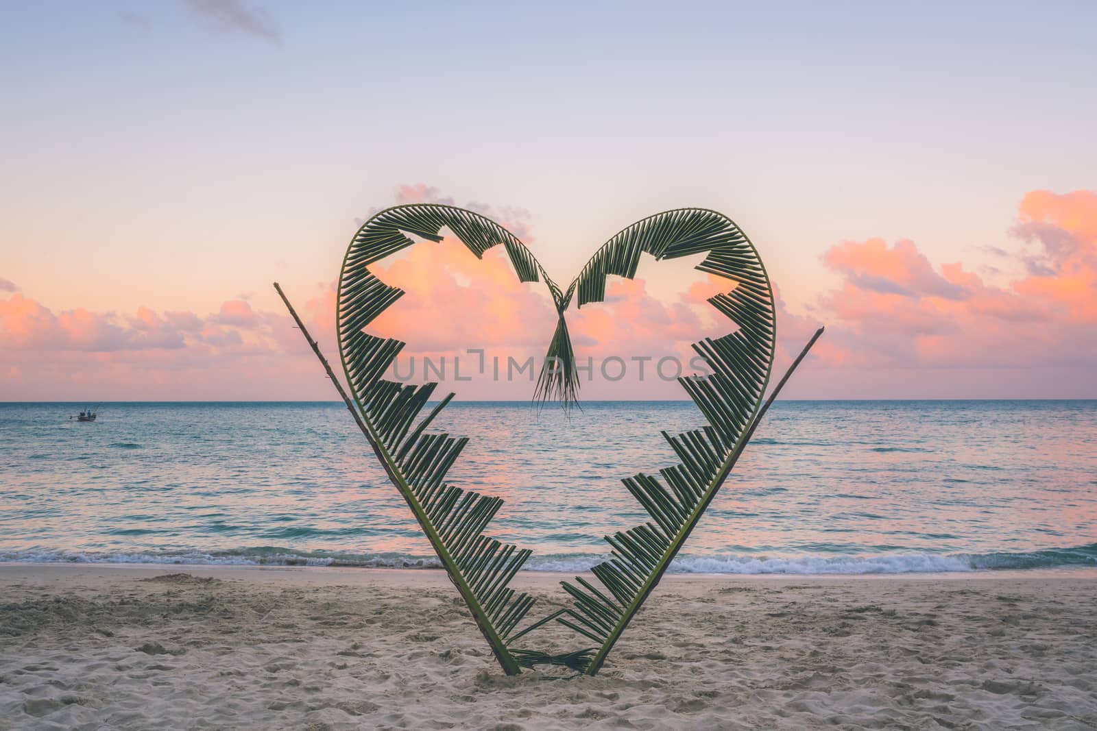 Palm tree branches are tied into the shape of a heart, on a quiet beach on the island of Koh Pha Ngan, Thailand .