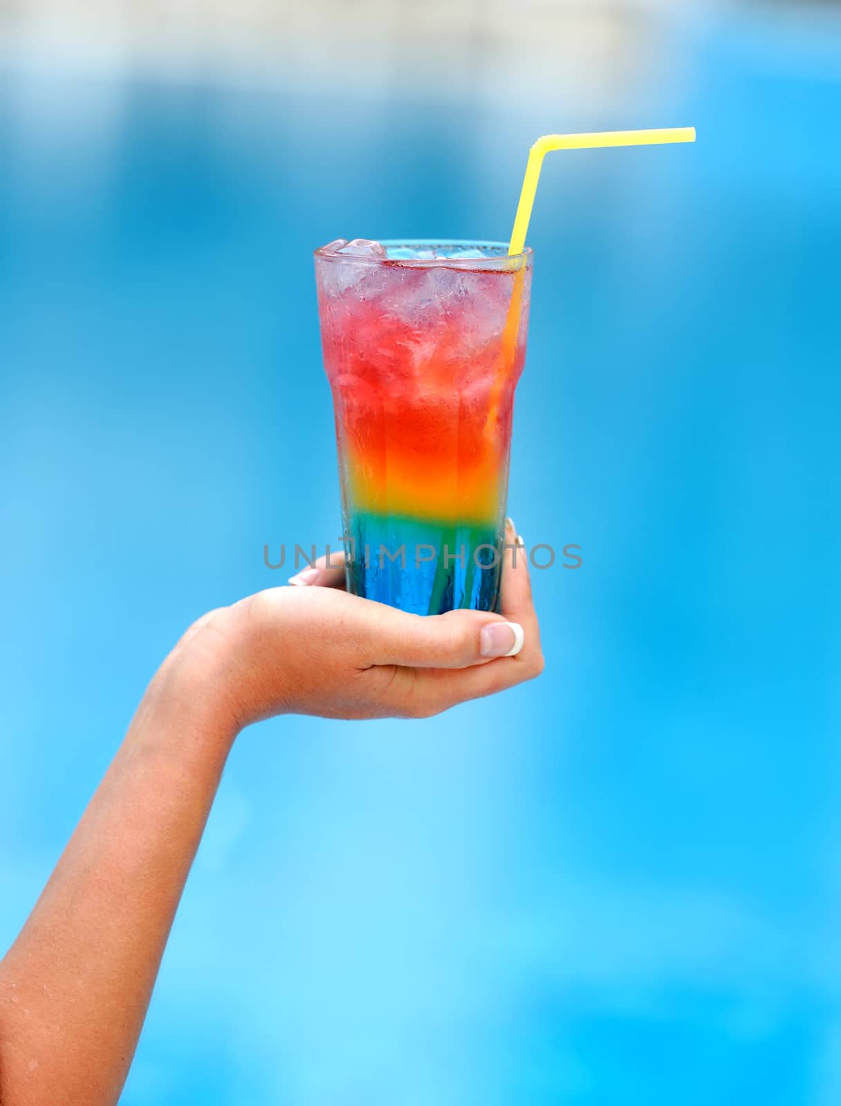 Woman hand with cocktail glass near swimming pool