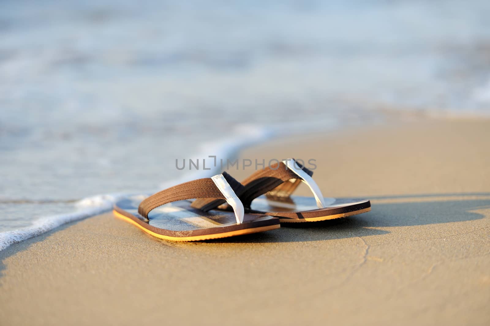 Summer vacation concept. Flip flops on a sandy ocean beach