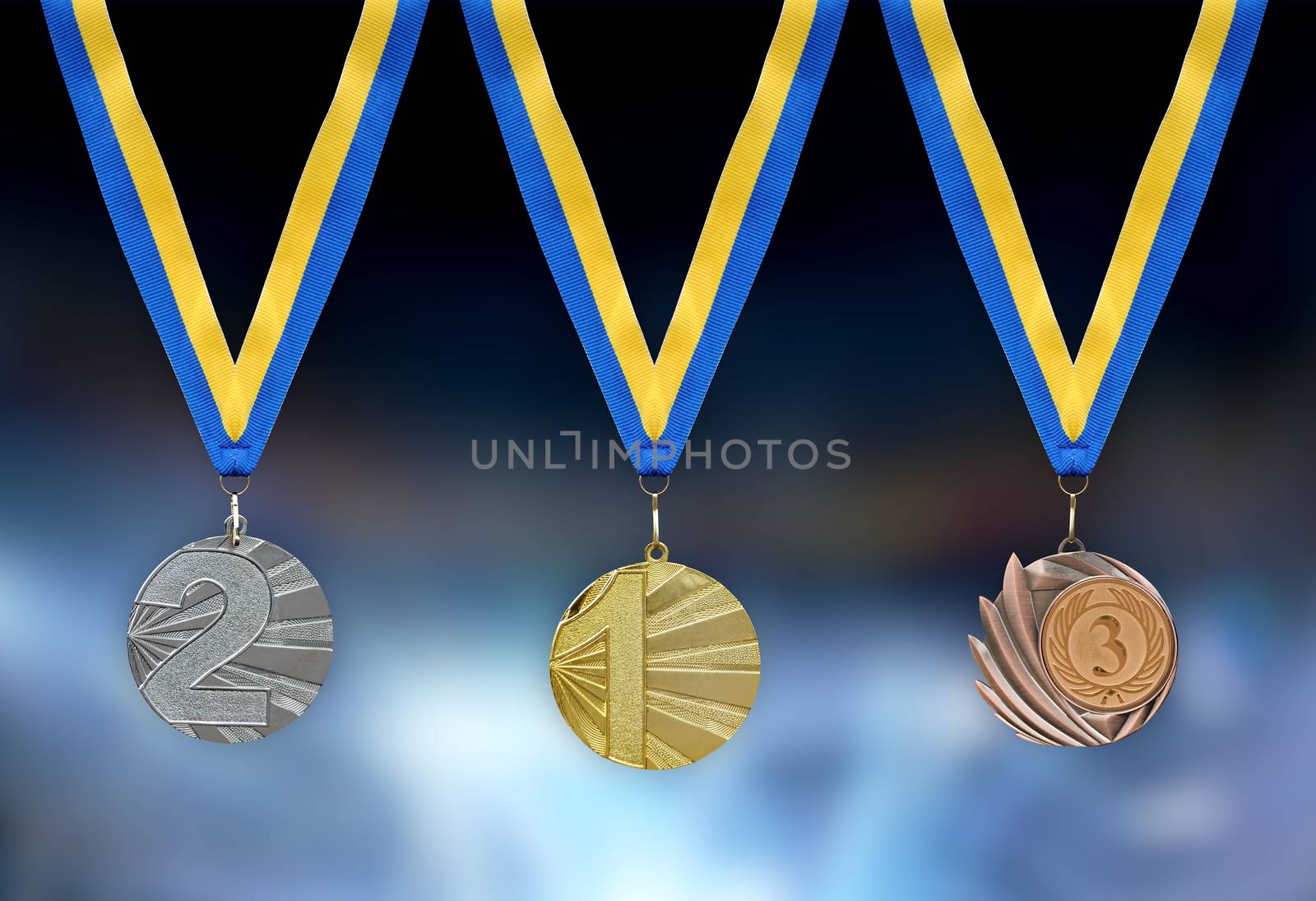 Gold, silver and bronze medals in the foreground with yellow blue ribbon
