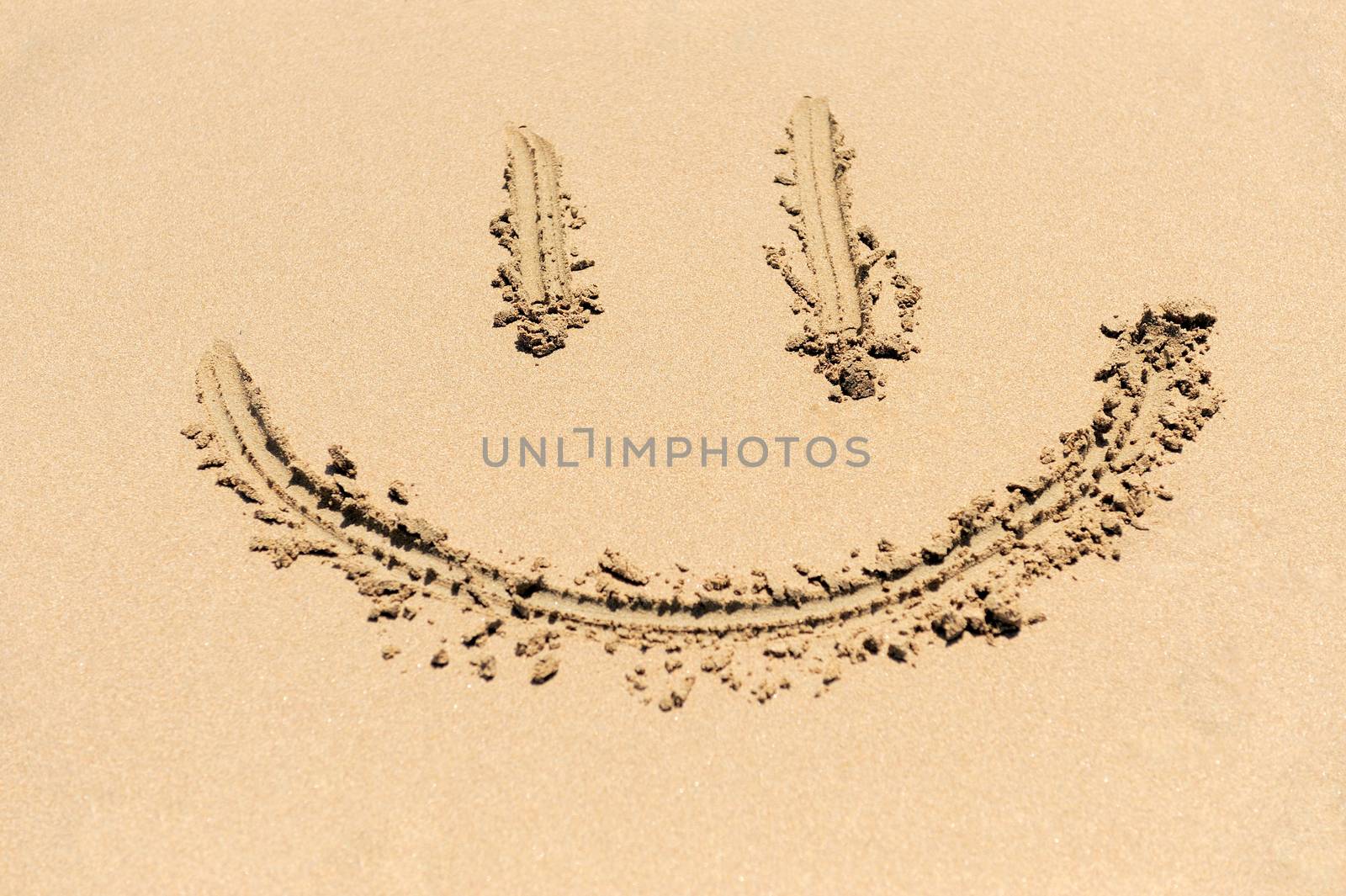 A smiley face drawing on a sand