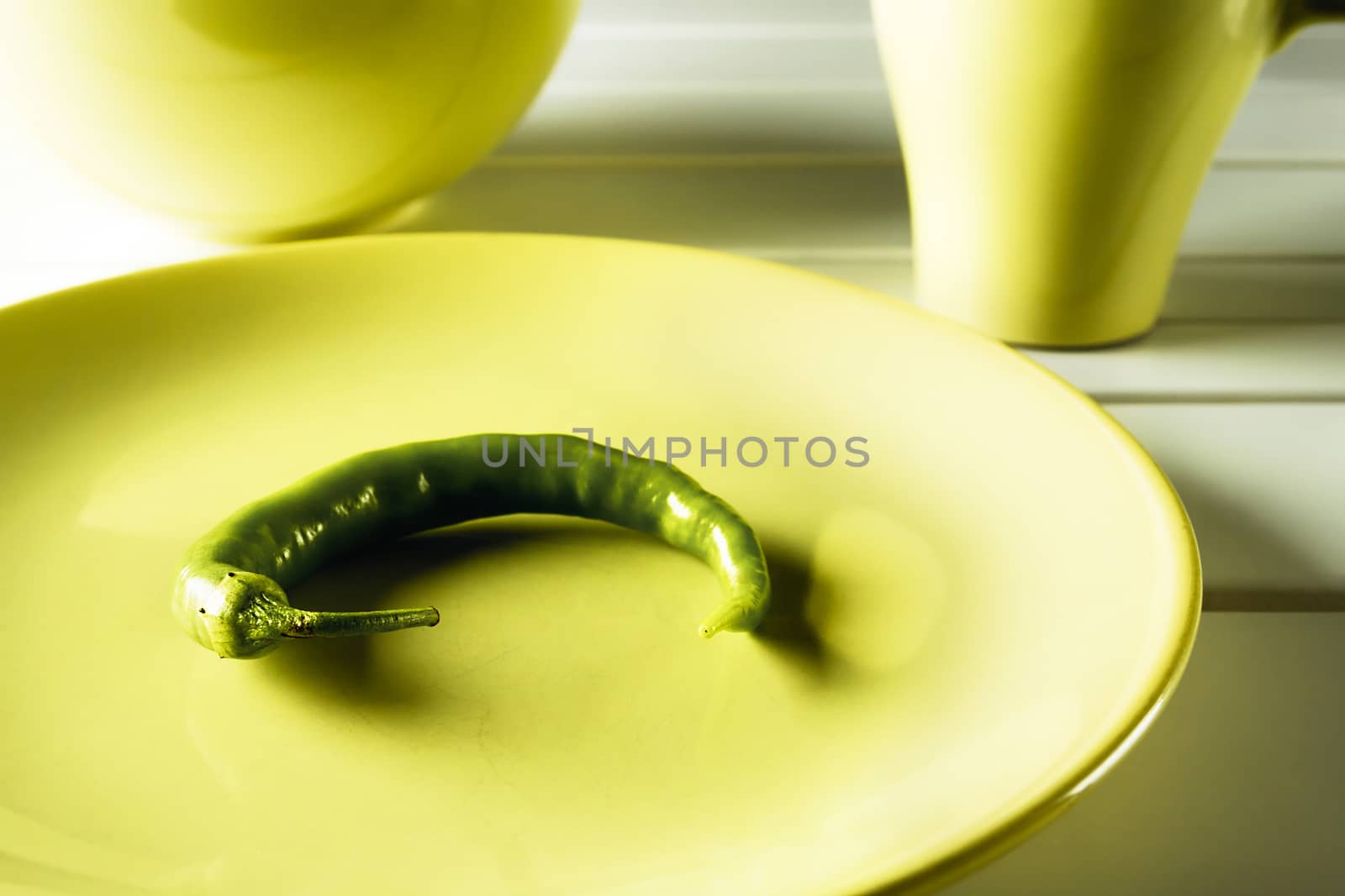 Green hot pepper on green dish over white wood. Horizontal image.