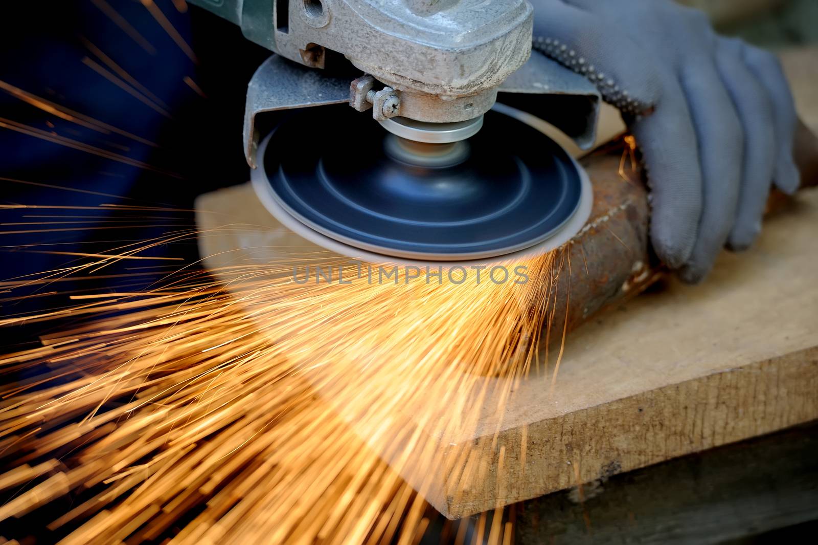 Worker cutting metal with grinder. Sparks while grinding iron