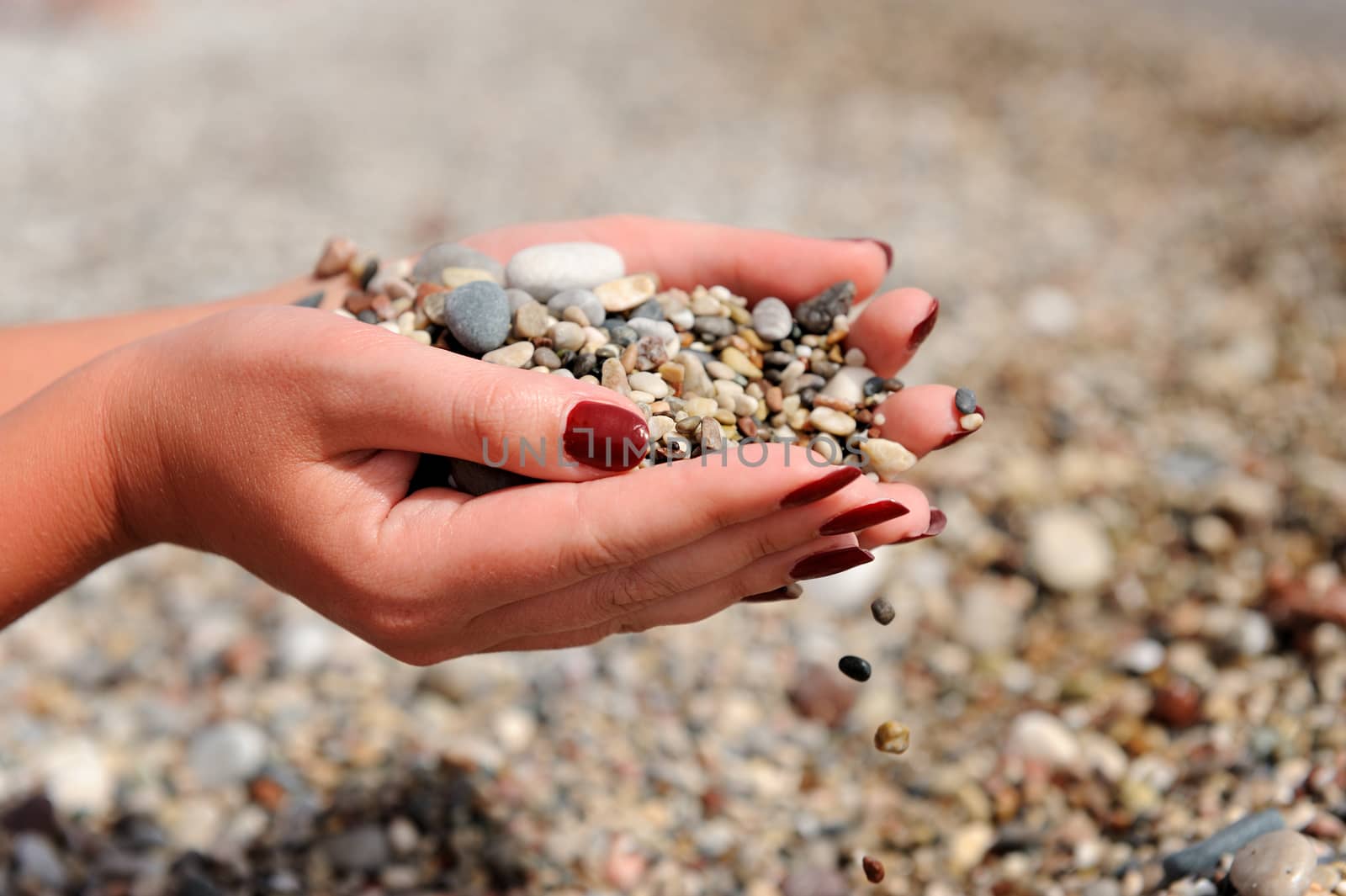 Hands dropping small stones on the beach