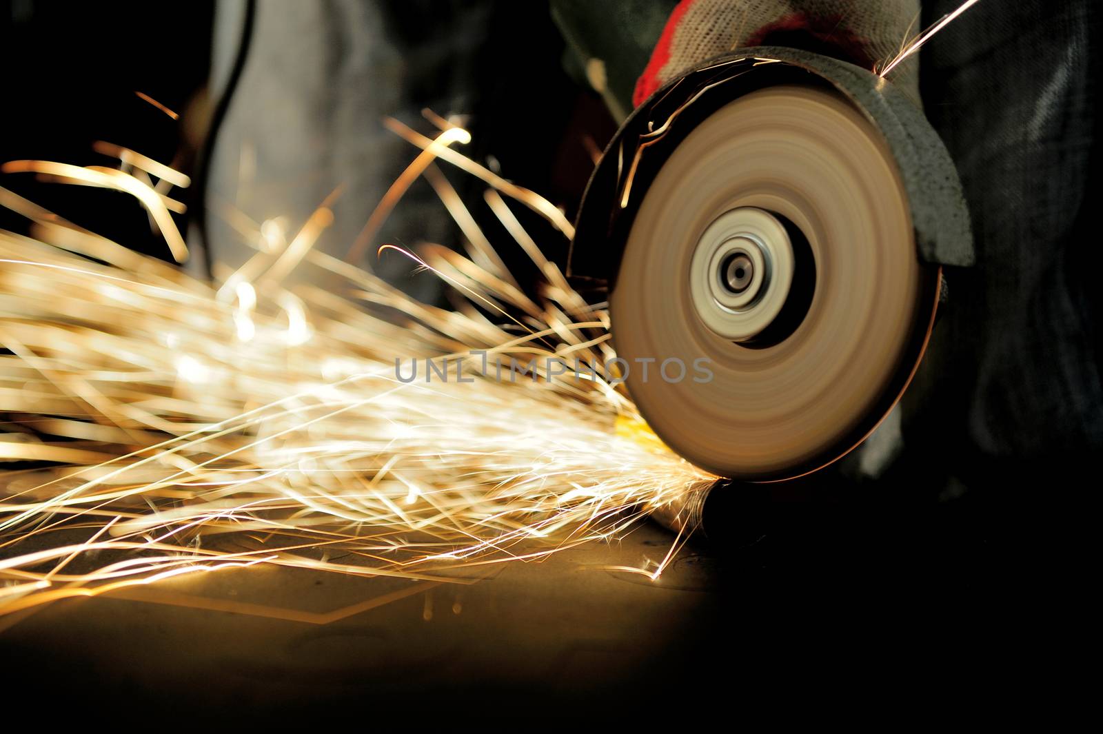 Worker cutting metal with grinder. Sparks while grinding iron