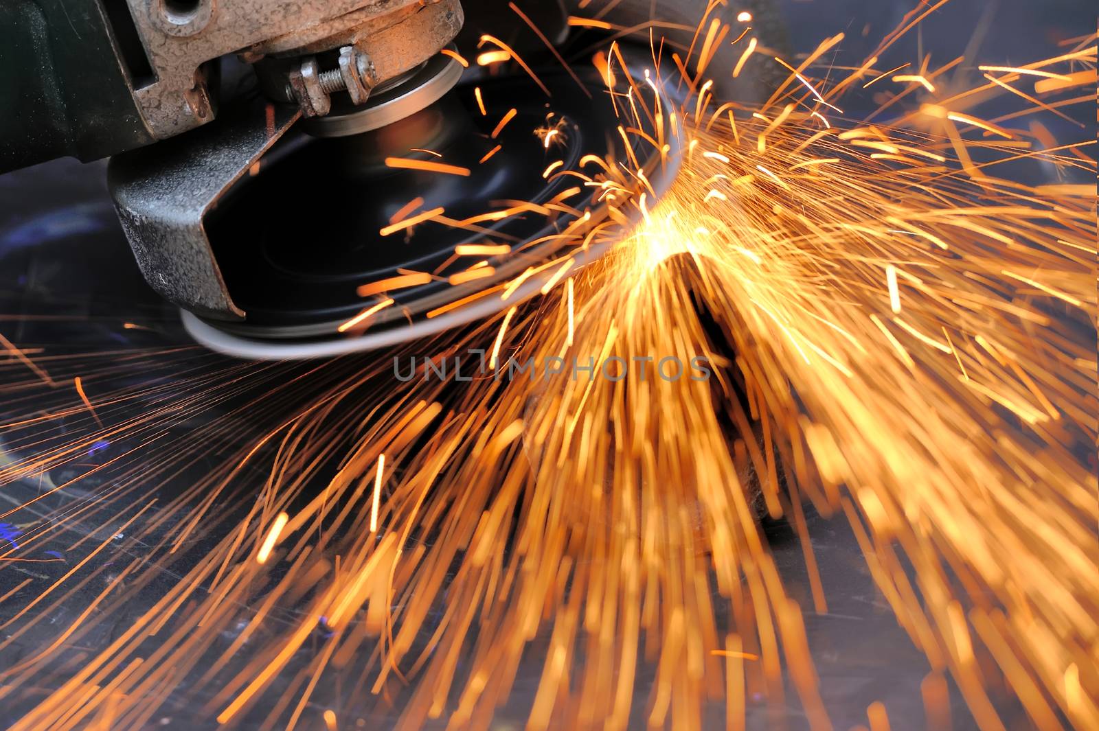 Worker cutting metal with grinder. Sparks while grinding iron