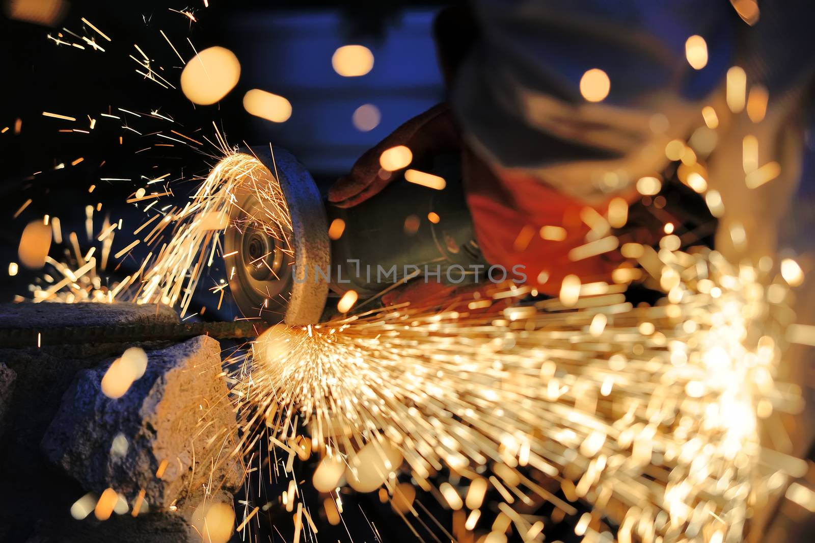 Worker cutting metal with grinder. Sparks while grinding iron