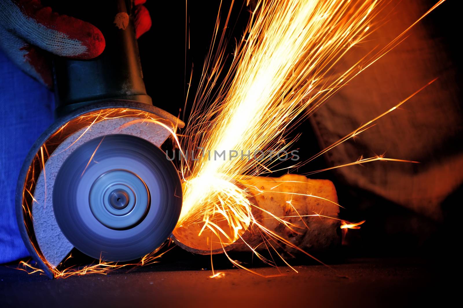 Worker cutting metal with grinder. Sparks while grinding iron