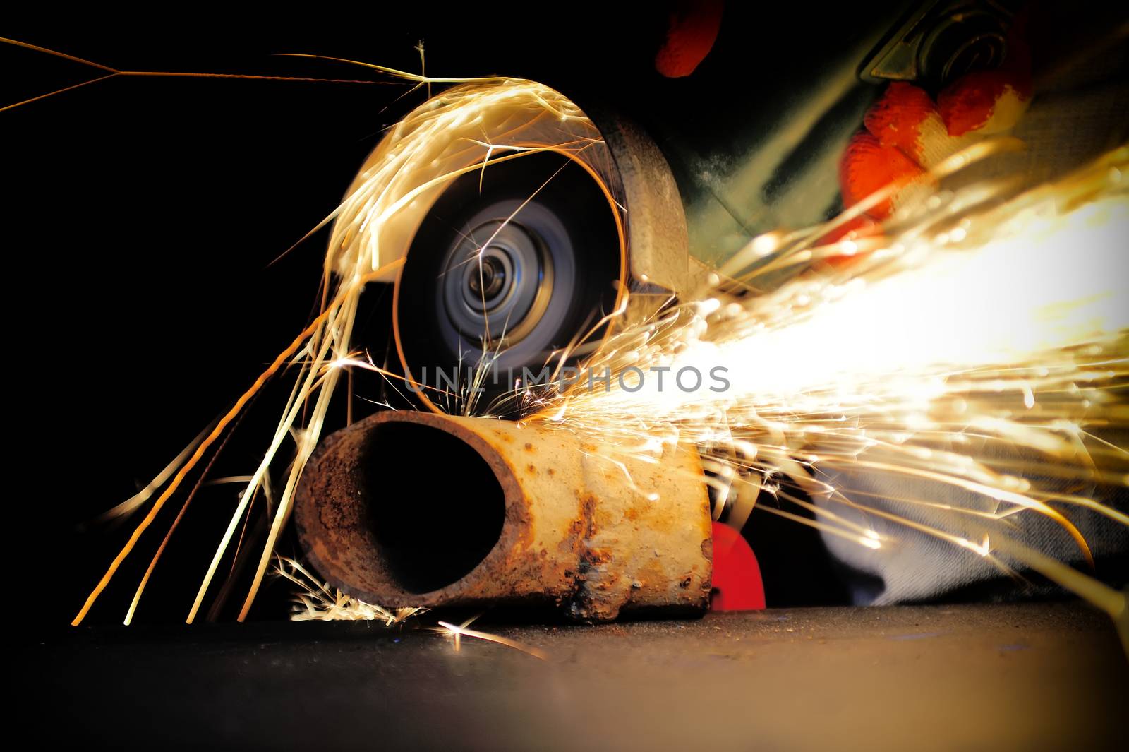 Worker cutting metal with grinder. Sparks while grinding iron