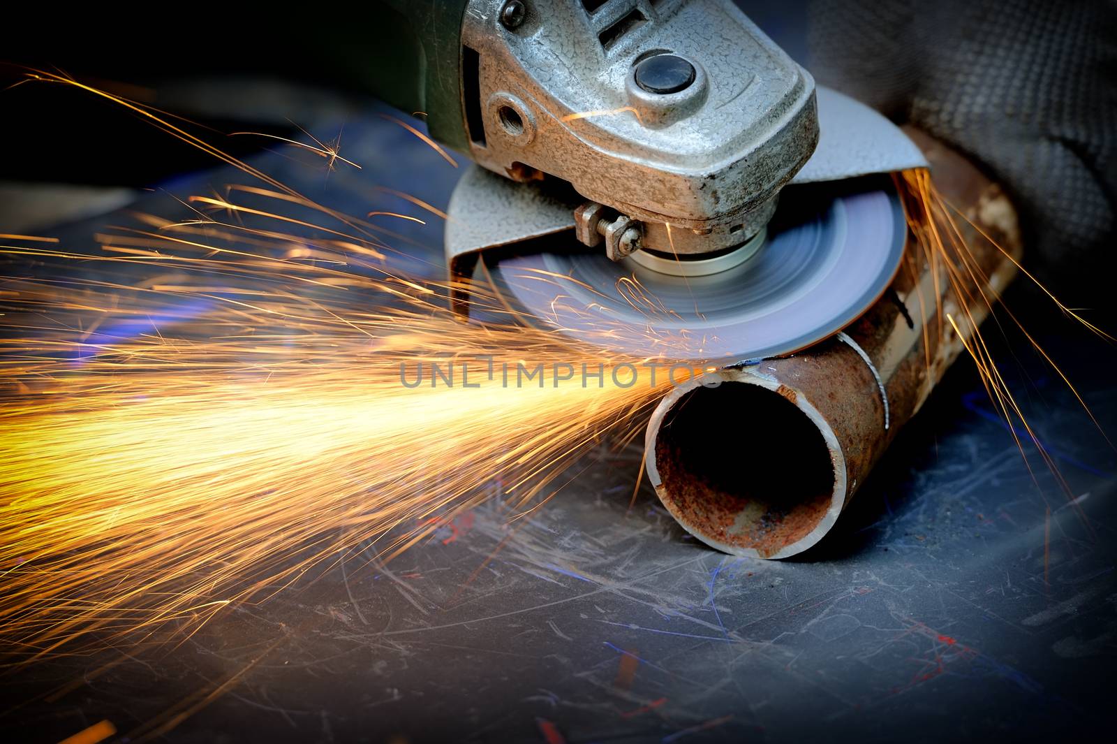 Worker cutting metal with grinder. Sparks while grinding iron