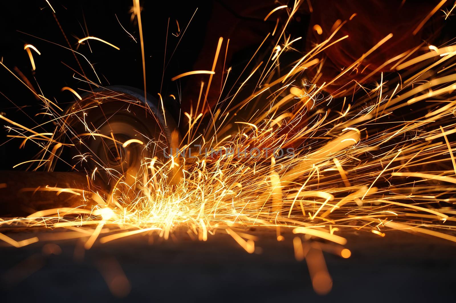 Worker cutting metal with grinder. Sparks while grinding iron