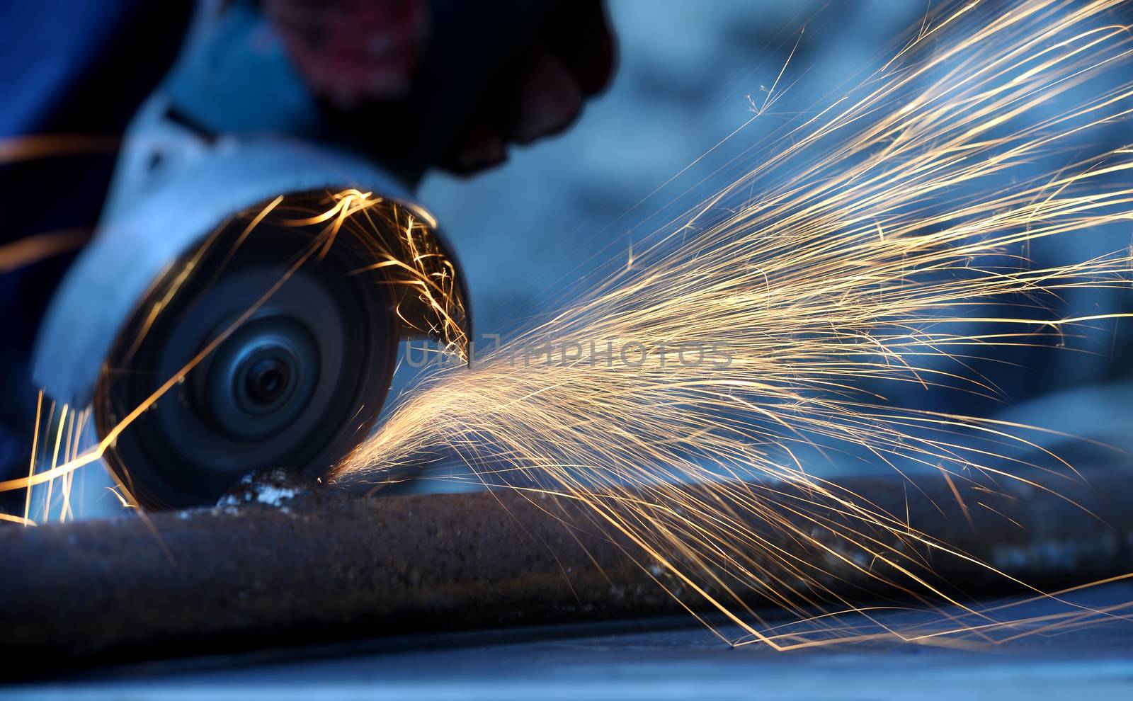 Worker cutting metal with grinder. Sparks while grinding iron