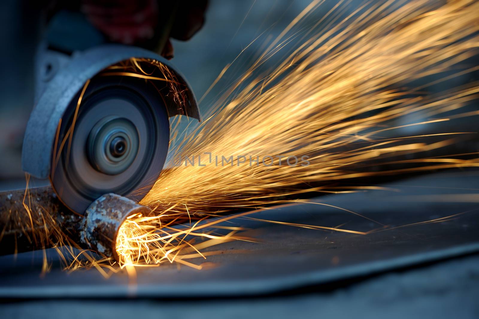 Worker cutting metal with grinder. Sparks while grinding iron