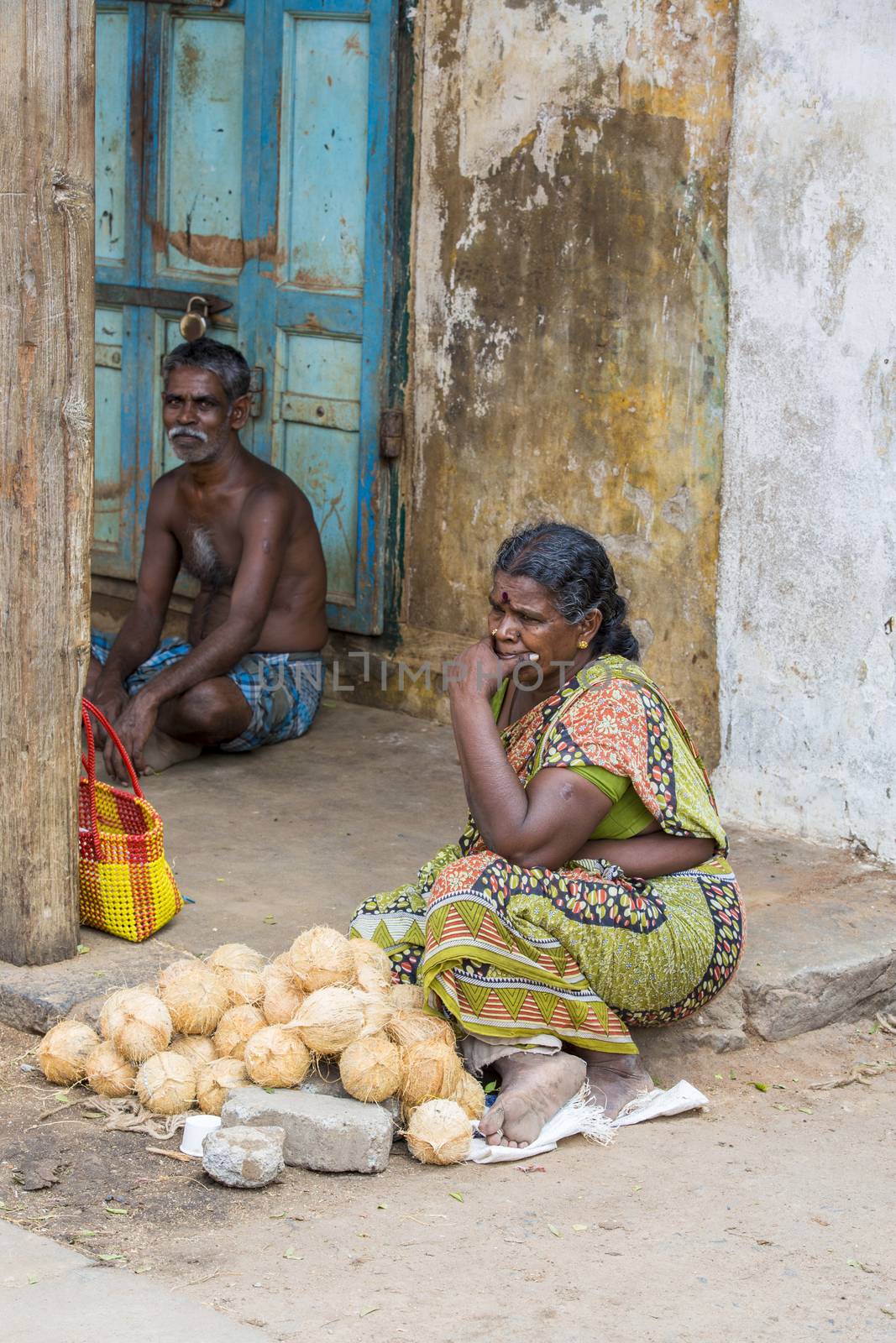 Documentary editorial image. Pondicherry, Tamil Nadu, India - May 28 2014. Very poor man and woman sitting in the street, trying to sell their fruits for money. Poverty in the world