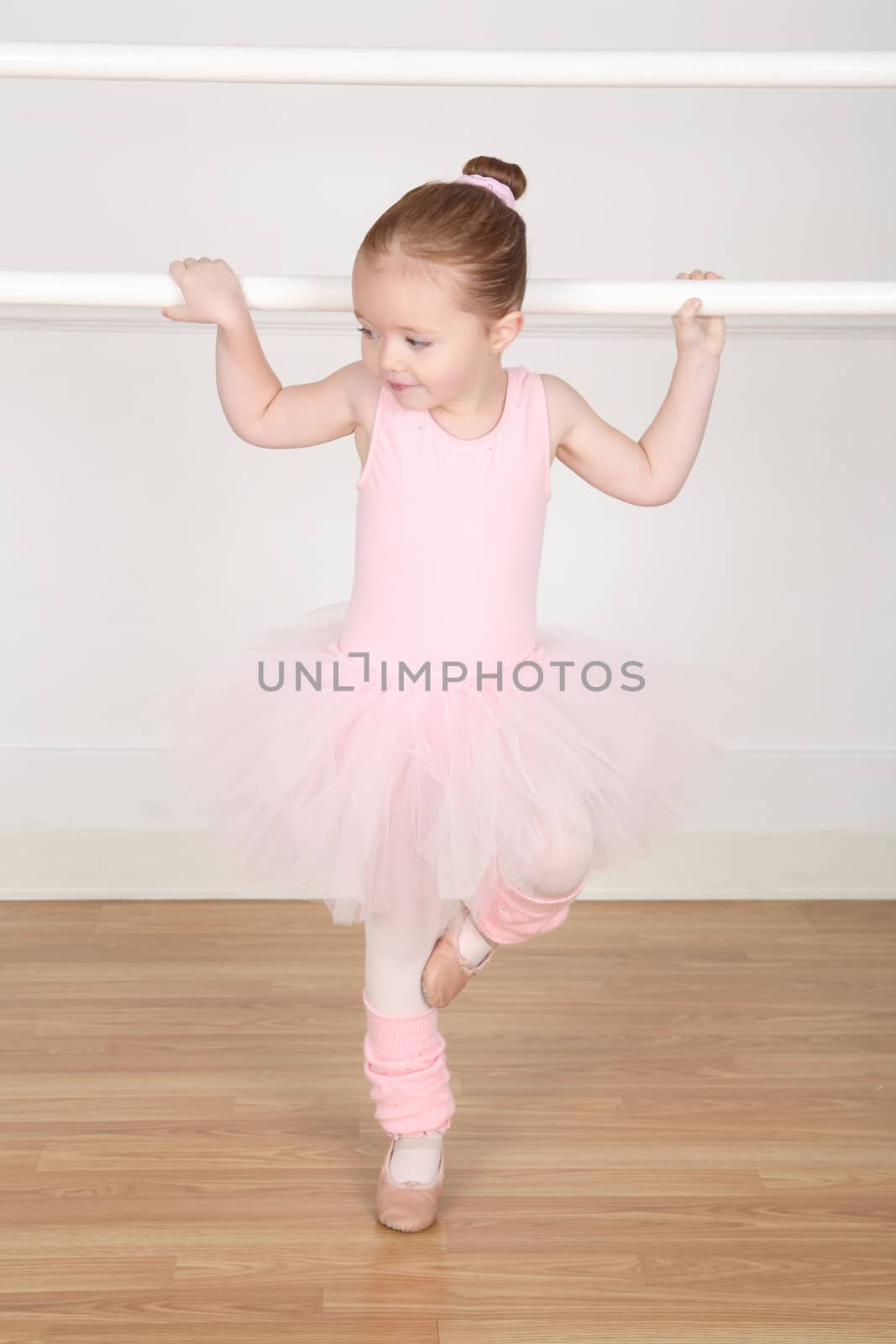 Little ballerina wearing a tutu dancing at the barre