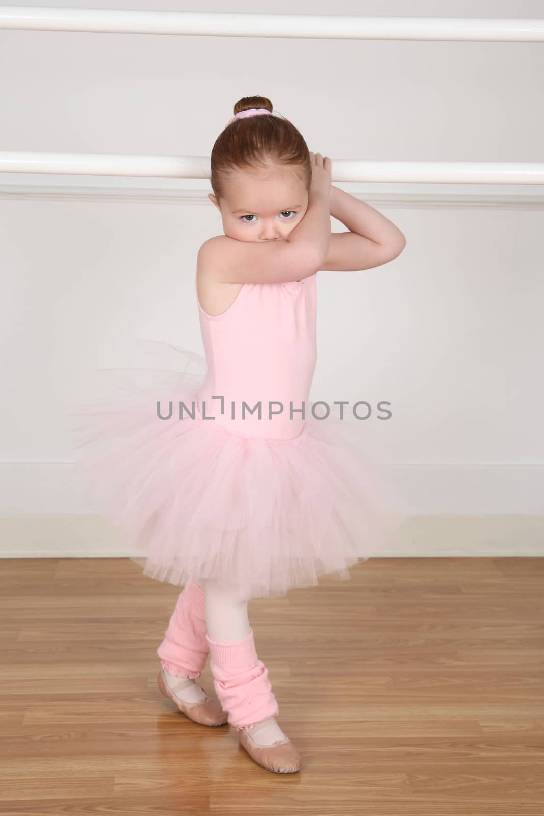 Little ballerina wearing a tutu dancing at the barre