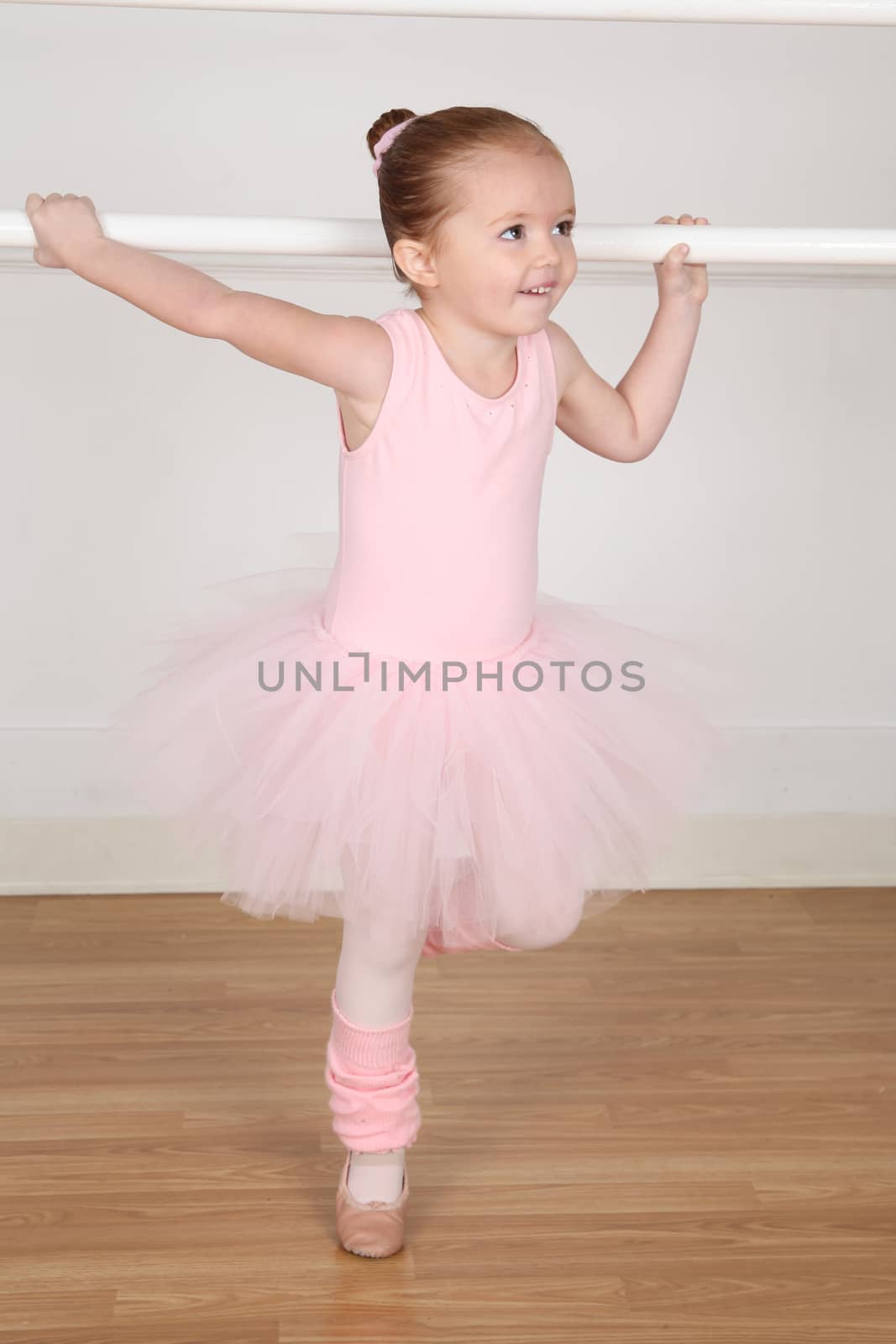 Little ballerina wearing a tutu dancing at the barre