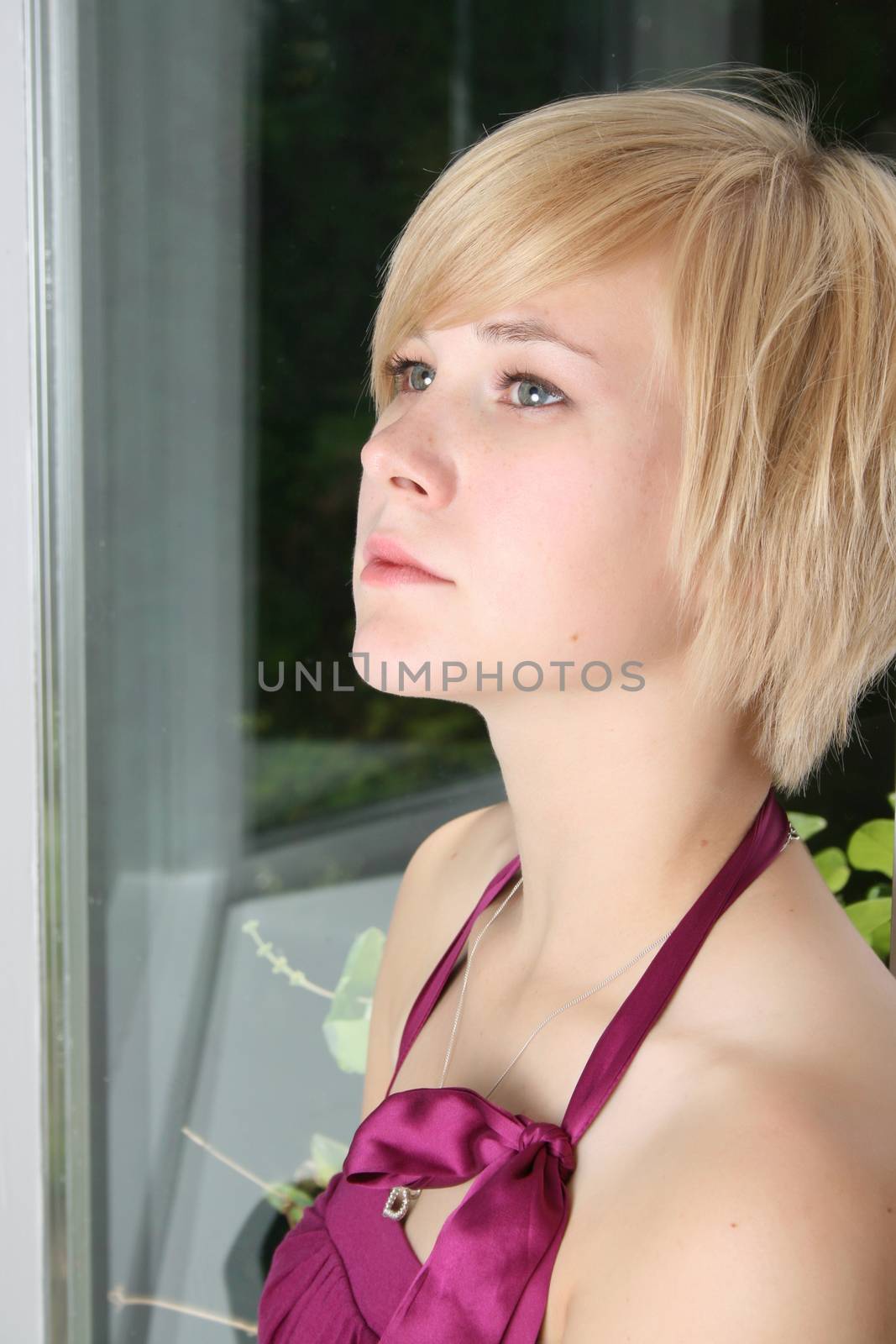 Beautiful blond female leaning against a door, expressing sadness and loneliness