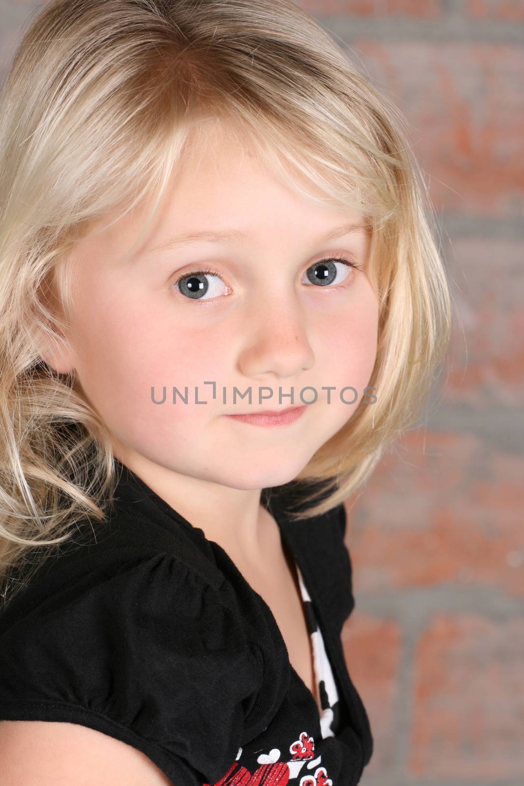 Little blond girl against a brick background