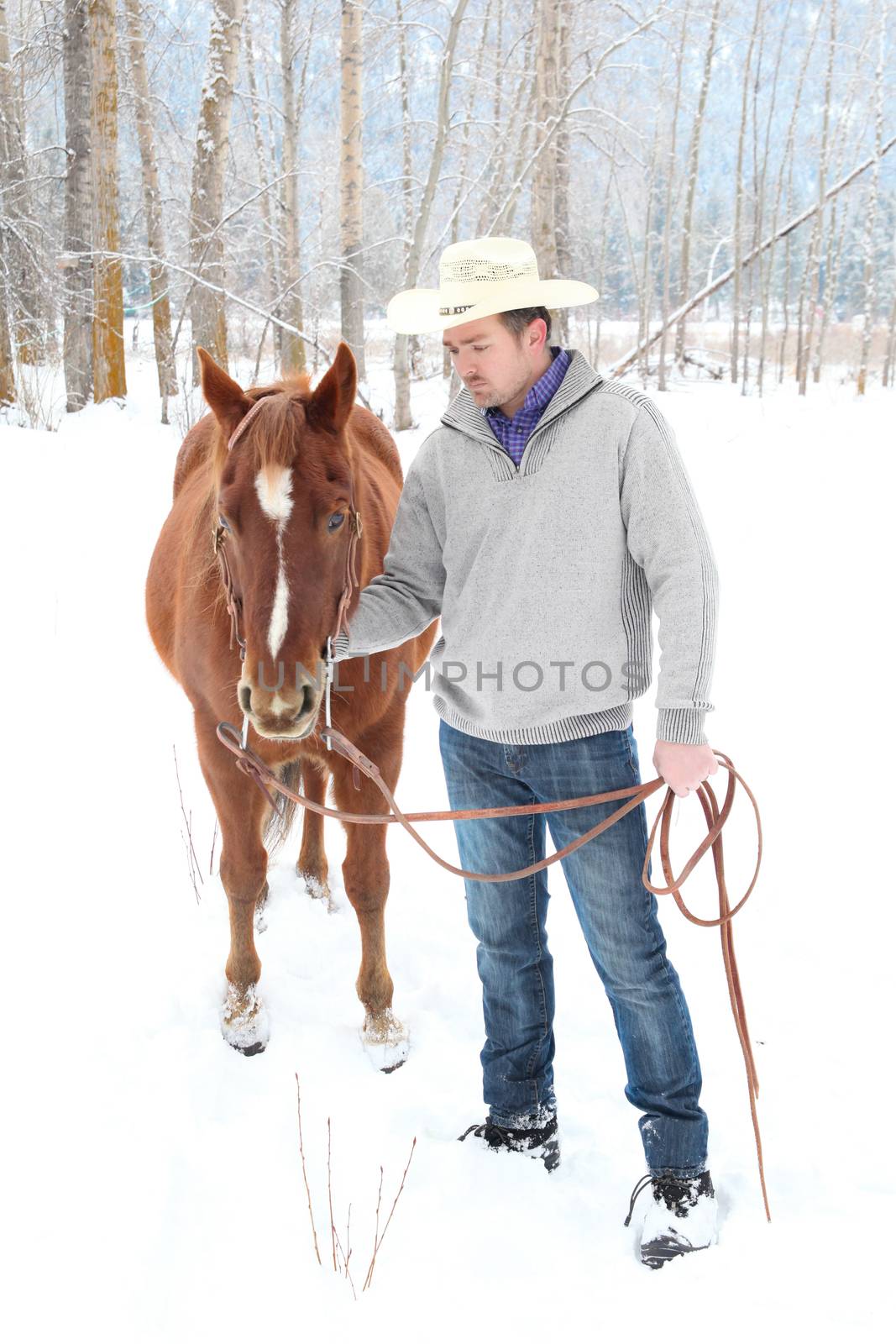 Young cowboy with his horse in a snow forest