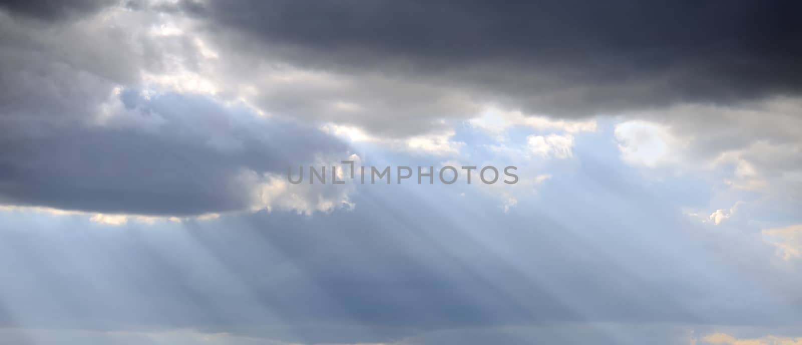 Light rays shine through the dark clouds by byrdyak