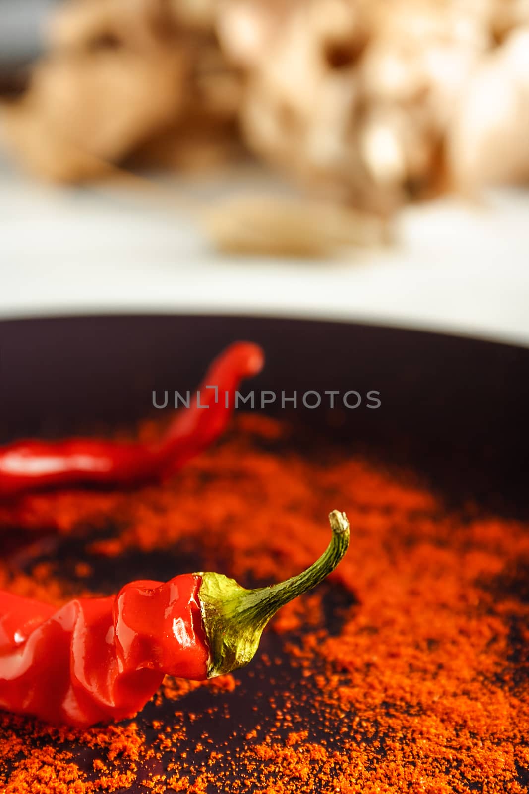 Closeup red pepper with ground paprika on brown dish over white wood. Vertical image.