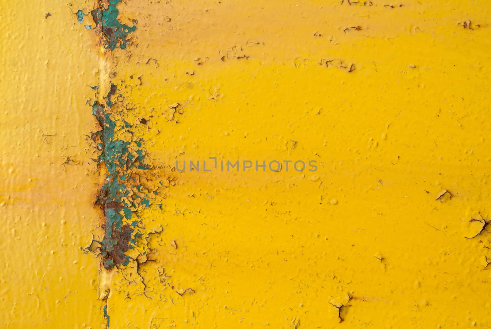 fragment of an iron surface is covered with yellow color paint, which has long been under the influence of different climatic conditions