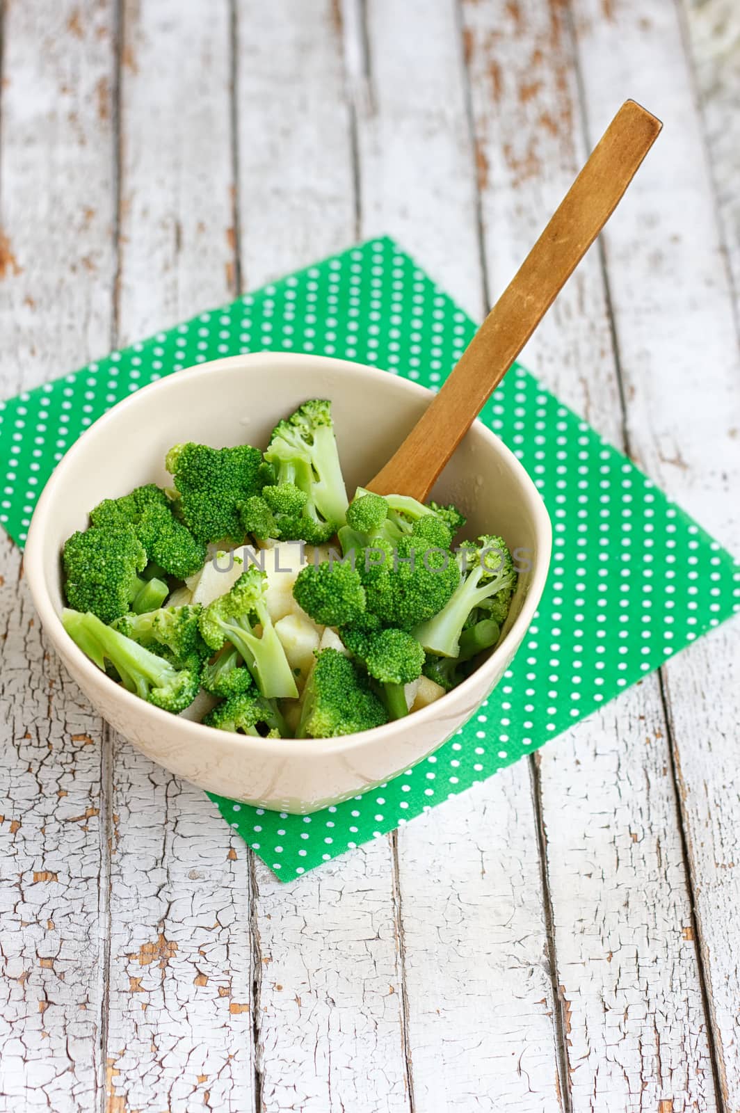 Salad in a deep bowl, broccoli, pepper and apple. On a wooden background