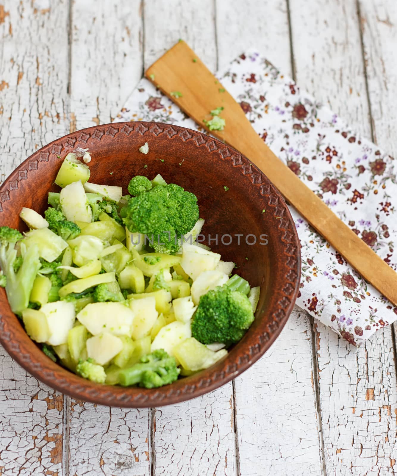 Salad in a deep bowl, broccoli, pepper and apple. On a wooden background