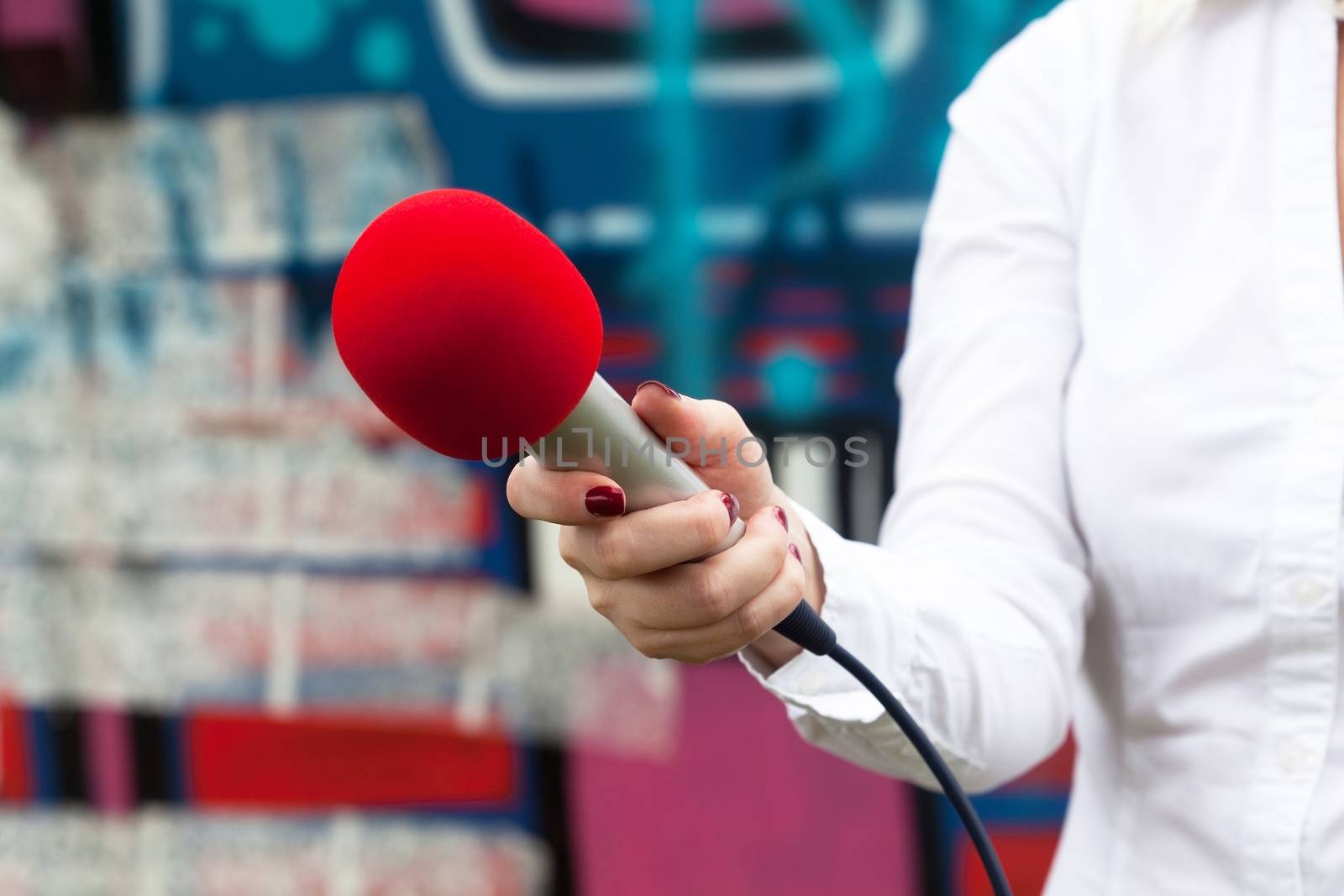 Female reporter at news conference, holding red microphone